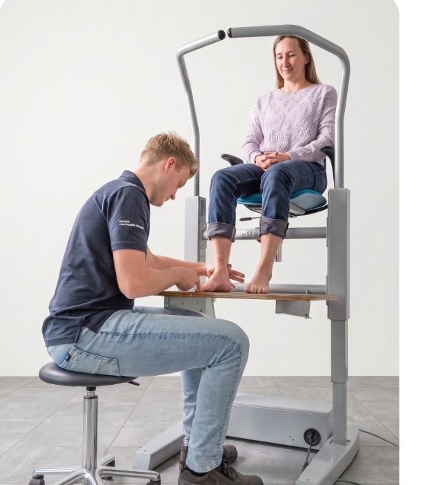 The specialist seated, assessing the client's foot at working height
